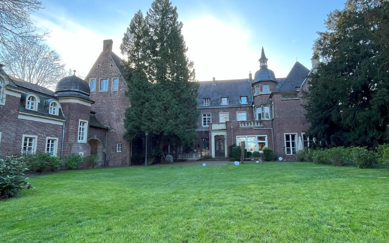Schloss Elbroich in Düsseldorf-Holthausen mit einer Wiese im Vordergrund