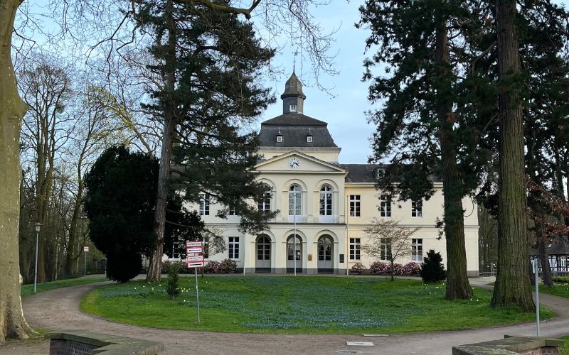 Das imposante Schloss Eller mit Bäumen und einer Wiese davor
